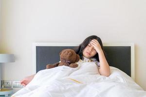 Aziatisch kind schattig of kind meisje slaap hoofdpijn ziek en hand- naar de voorhoofd foto