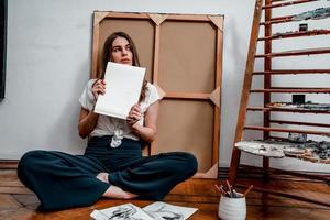 portret van een mooi jong artiest, trekt afbeeldingen in de werkplaats foto