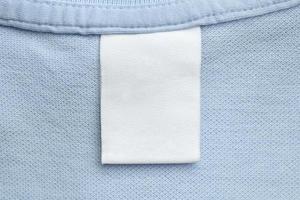 wit blanco wasserij zorg kleren etiket Aan blauw overhemd kleding stof achtergrond foto