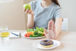 eetpatroon, dieet Aziatisch jong vrouw of meisje gebruik hand- Duwen uit, ontkennen zoet donut en Kiezen groen salade groenten, eten voedsel voor mooi zo gezond, Gezondheid wanneer hongerig. dichtbij omhoog vrouw gewicht verlies persoon. foto