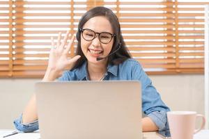 video telefoongesprek, vergadering conferentie, gelukkig Aziatisch jong vrouw, meisje vervelend bril studie, leren online, gebruik makend van laptop computer of notitieboekje via internetten. freelancer werken van huis, technologie. foto