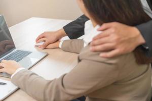 ongelukkig, hand- van Aziatisch jong vrouw medewerker, Mens werkgever of collega of baas aanraken haar hand- en omarmen, gevoel walgen, ongemakkelijk. seksueel Intimidatie ongepast Bij werkplek. foto