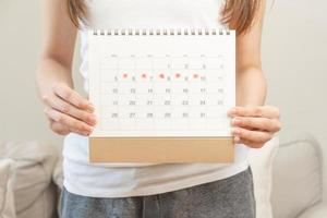 menstruatie, periodes fiets dag van maandelijks, pijn doen Aziatisch jong vrouw, vrouw hand- vasthouden, markering symbool Aan kalender voor gemist en vertraging of laat. medisch, gezondheidszorg, gynaecologisch concept. kopiëren ruimte foto