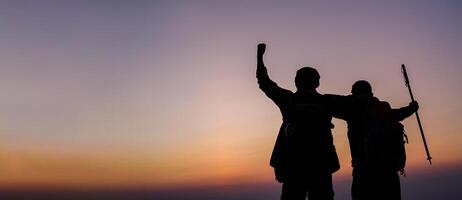 silhouet van juichen wandelen paar Open armen naar de zonsopkomst staan Bij Aan berg foto