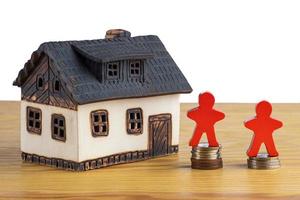huis met stapels van geld en een figuur model- symboliseert stijgende lijn echt landgoed prijzen. foto