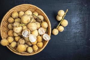 longkong of langsat fruit in een rieten mand op een zwarte houten achtergrond foto