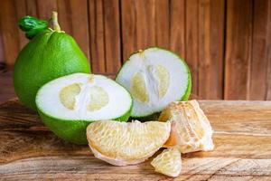 geheel, in plakjes gesneden en stukjes pomelo-fruit op een houten tafel foto