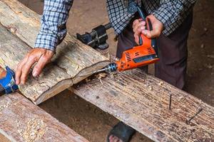 man met boormachine op de plank van hout in een houtbewerkingswinkel foto