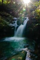 glad waterval smaragd kleur met zonnestraal foto