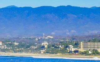 zon strand kliffen rotsen golven palmen bergen puerto escondido Mexico. foto