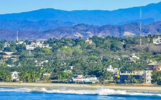 zon strand kliffen rotsen golven palmen bergen puerto escondido Mexico. foto