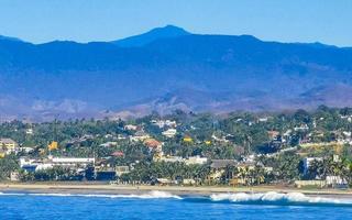 zon strand kliffen rotsen golven palmen bergen puerto escondido Mexico. foto