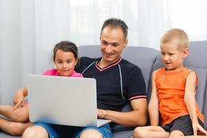 vader en kinderen tekenfilm online Bij laptop, vader uitgeven tijd samen met kind spelen spel met papa genieten van ochtend- Bij huis foto