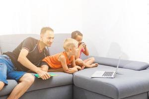 kinderen en hun vader gebruik makend van een laptop, online aan het leren Bij huis foto