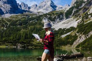 jong vrouw reiziger met een kaart Aan de achtergrond van de Alpen. actief vrije tijd, levensstijl sport, wandelen in de bergen. op reis in Europa. foto