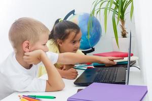 covid-19 coronavirus en aan het leren van huis, huis school- kind concept. weinig kinderen studie online aan het leren van huis met laptop. quarantaine en sociaal afstand nemen concept. foto