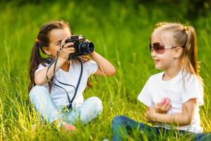 twee weinig meisjes zittend Aan gras foto