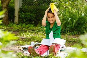 een schattig kind is lezing een boek in de park. foto