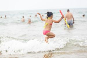 schattig weinig meisje zittend Bij oceaan strand foto