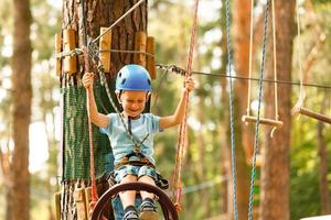 schattig kinderen. jongen beklimming in een touw speelplaats structuur Bij avontuur park foto