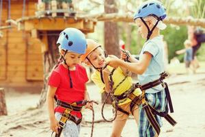 schattig kinderen. jongen en meisje beklimming in een touw speelplaats structuur Bij avontuur park foto