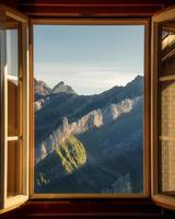 een berg landschap gefotografeerd van een huis, de venster vormen de kader van de beeld foto