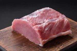 vers sappig varkensvlees Aan een houten snijdend bord met specerijen en zout foto