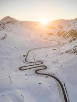 slang vormig voorbij gaan aan weg in winter gedurende zonsondergang foto