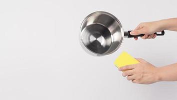 pot schoonmaak Mens hand- Aan wit achtergrond schoonmaak de niet stok pot met handig schotel het wassen spons welke geel kleur Aan de zacht kant en groen Aan moeilijk kant voor hygiëne na koken. elektrisch pot foto