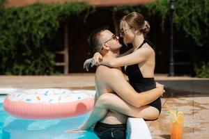 vent en een meisje in het baden pakken zijn ontspannend, in de buurt de blauw zwembad foto