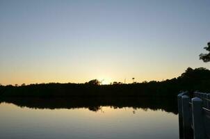 vijver of meer water Bij zonsondergang met bomen Bij schemer foto