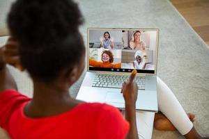 terug visie van vrouw spreken praten Aan video telefoontje met verschillend multiraciaal vrienden Aan online , vrouw hebben webcam groep conferentie met vrienden Aan modern laptop Bij huis foto