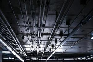 sanitair systeem pijpen en elektrisch kabels geïnstalleerd onder vlak plaat versterkt beton structuur in gebouw.ventilatie pijpen in ondergronds parkeren foto