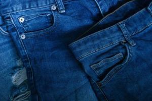blauw jeans broek kleren stapel achtergrond. stack van blauw jeans Aan winkel bureau, denim jeans achtergrond. vernietigd gescheurd klassiek denim blauw jeans pleisters, banier mode achtergrond foto