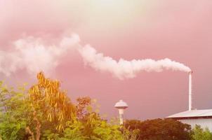 reusachtig fabriek schoorsteen vervuilend de lucht, hoog schoorsteen emitting water damp en rook vervuiling, industrie veroorzaken verontreiniging foto