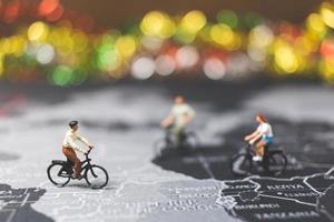 miniatuurreizigers fietsen op een wereldkaart, reizen en het wereldconcept verkennen