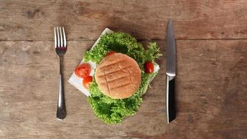 top visie van eetlust hamburger tegen een houten tafel. een mes en een vork liggen Aan de tafel. kopiëren ruimte foto