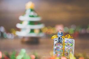 miniatuurmensen op geschenkdoos met kerstdag viering achtergrond foto
