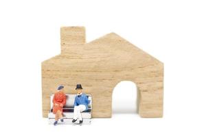 miniatuur man en vrouw zit voor een huis op een witte achtergrond, familie concept foto
