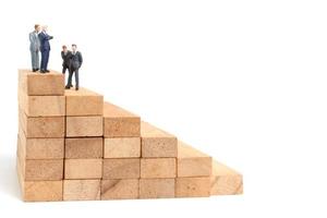 miniatuur ondernemers staan op houten blokken geïsoleerd op een witte achtergrond foto