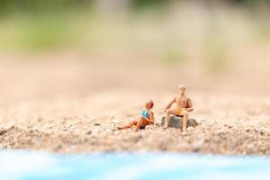 miniatuurmensen die zwemkleding dragen die op een strand, de zomerconcept ontspannen
