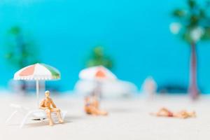 miniatuurmensen die zwemkleding dragen die op een strand, de zomerconcept ontspannen