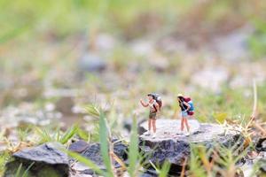 miniatuurreiziger met rugzakken die in het veld-, reis- en avontuurconcept lopen foto