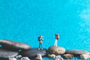 miniatuur backpackers, toeristenmensen op een blauwe glitterachtergrond