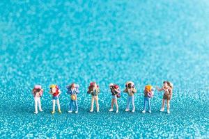 miniatuur backpackers, toeristenmensen op een blauwe glitterachtergrond foto