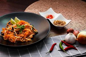 Thais voedsel stootkussen Thais Thais nationaal schotel stootkussen Thais Aan zwart bord met limoen en kruiden. foto