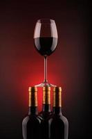 wijnflessen en vol glas met rode en zwarte achtergrond foto
