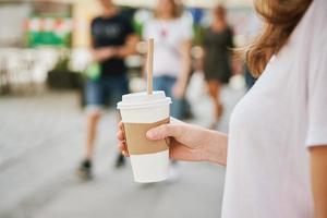 vrouw wandelingen Bij stad straat met papier koffie beker. foto