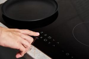 vrouw hand- bochten Aan modern inductie fornuis in de keuken foto