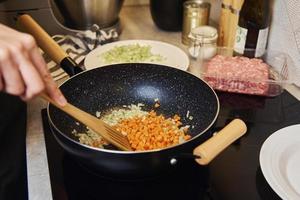 vrouw Koken saus bolognese in keuken foto